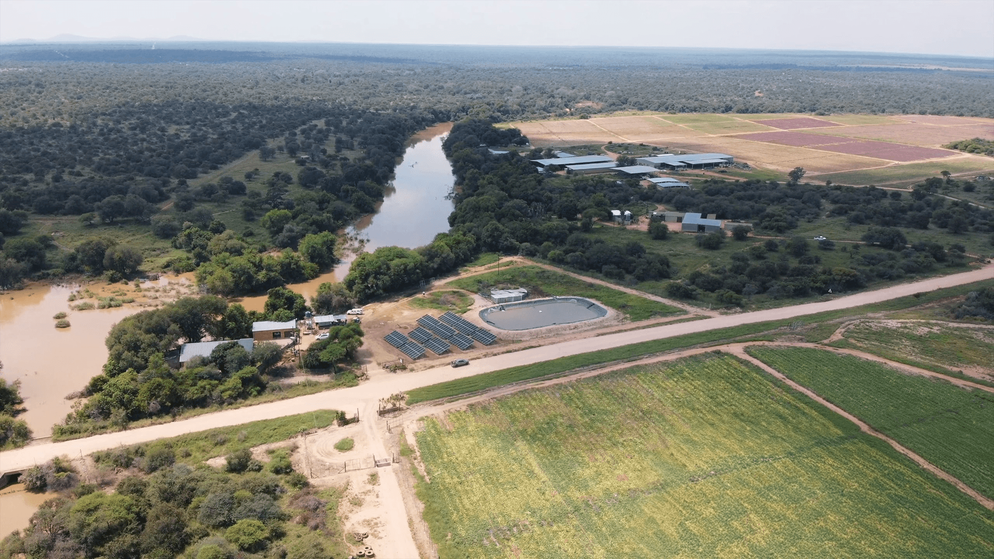 Modern two-story house with glass railings and stone facade, surrounded by desert landscaping. Prominent "For Sale" sign in the foreground under a clear blue sky.