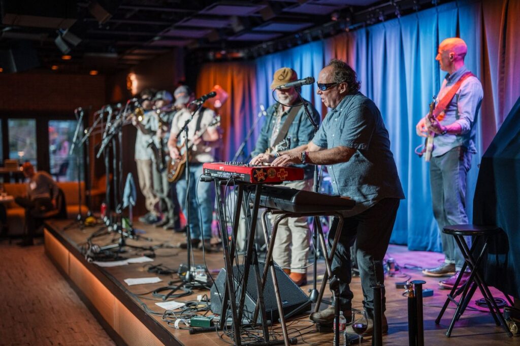 Keyboard player and full band performing at Paul JAS Center Aspen evening event under blue and amber stage wash lighting