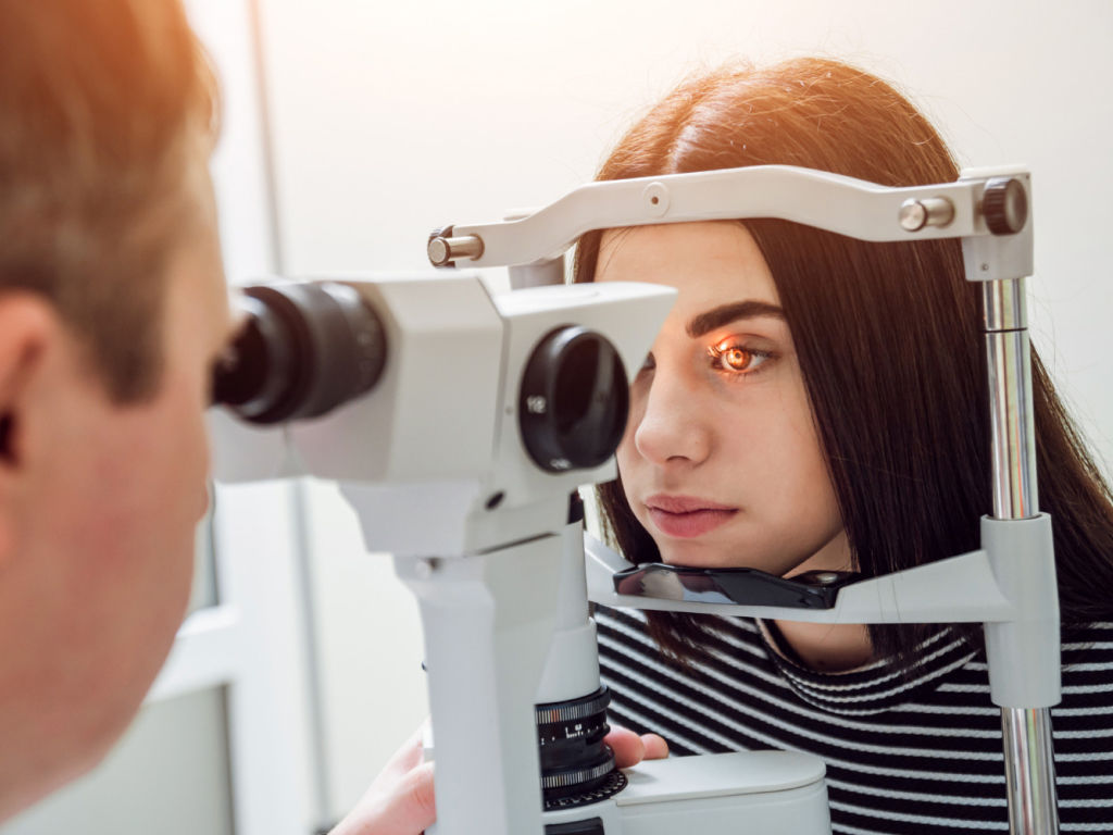 A woman undergoing an eye exam, focusing on the chart in front of her to assess her vision.