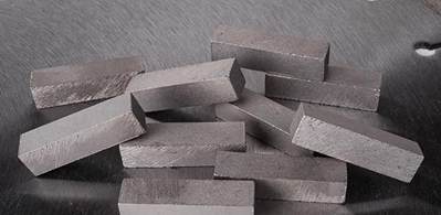 A pile of rectangular diamond segments with a rough surface, scattered on a reflective surface. These segments are designed for heavy-duty cutting tasks such as stone or concrete cutting.