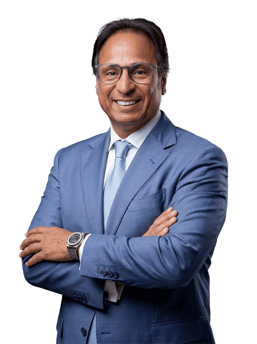 Man with a beard in a dark button-up shirt, smiling while writing in a notebook.