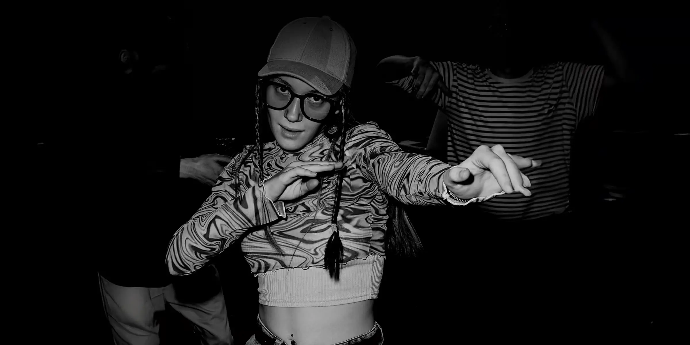 Black and white photo of a person mid-movement in a club-like setting, suggesting individuality, expression, and underground culture.