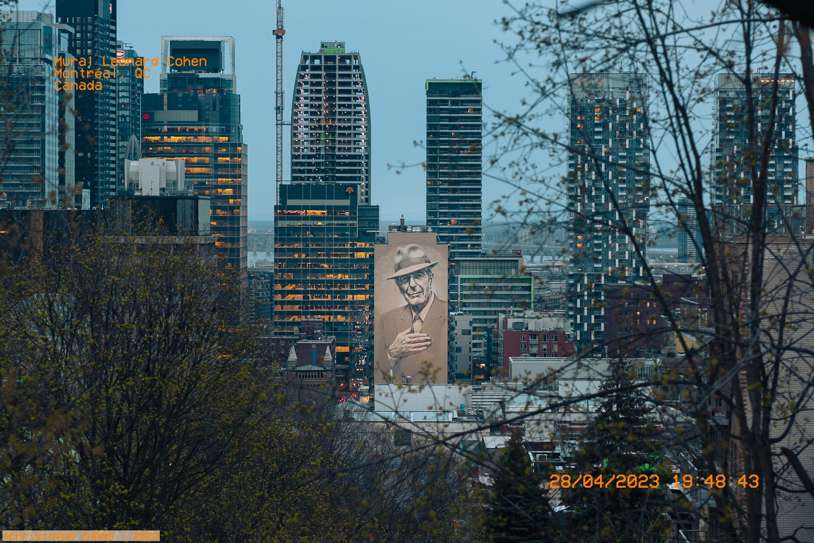 Fresque de Leonard Cohen dominant la skyline de Montréal au crépuscule