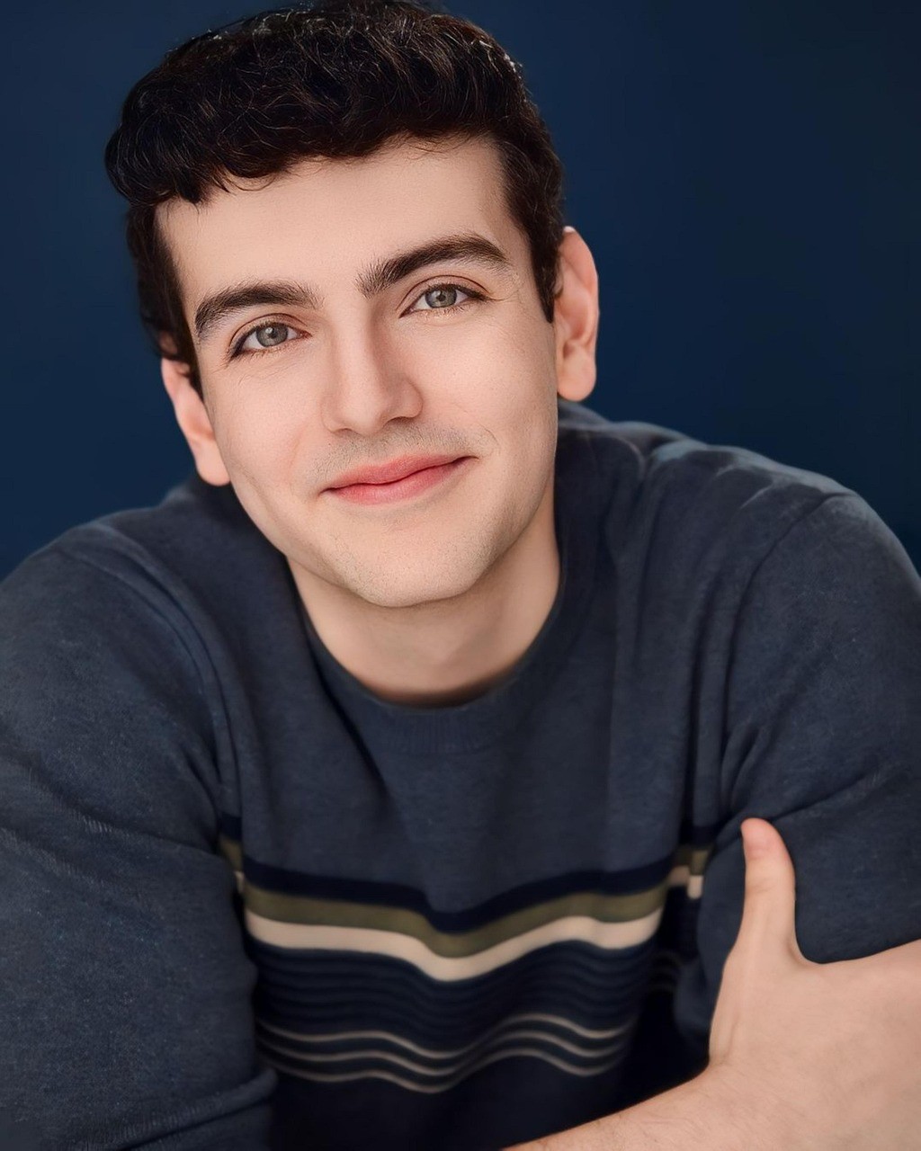 man in white sweater holding round mirror