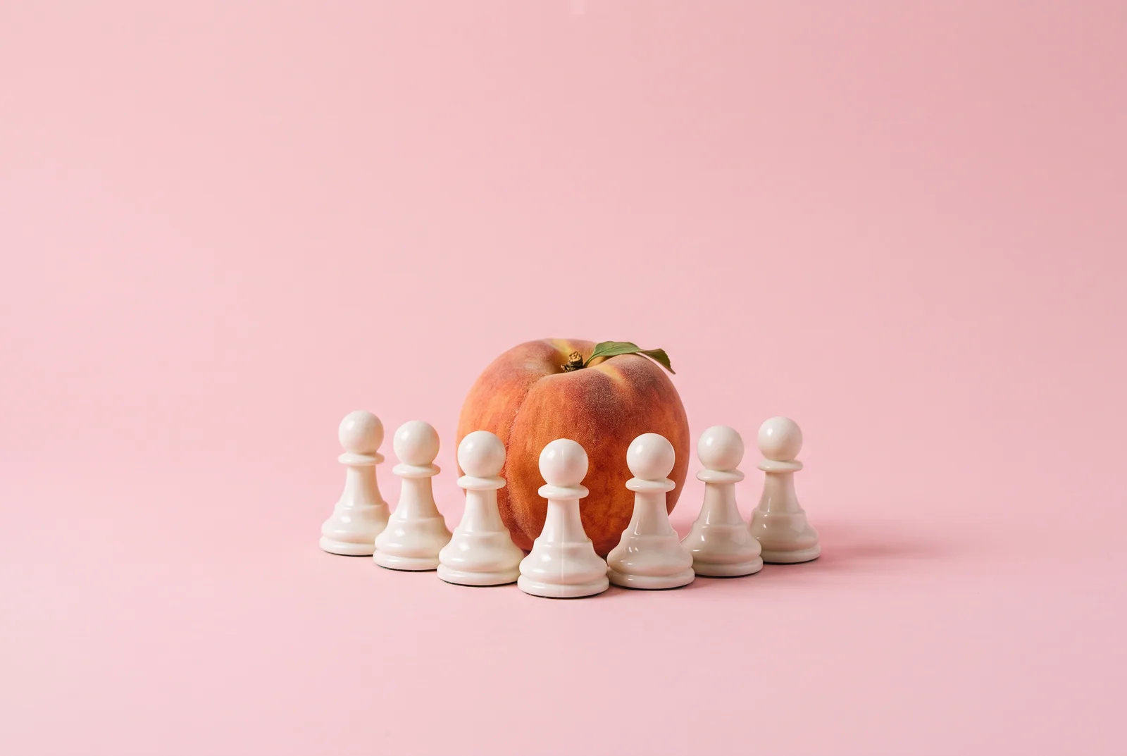 A peach behind a row of white chess pawns forming a small wall, safety and boundaries in betrayal trauma