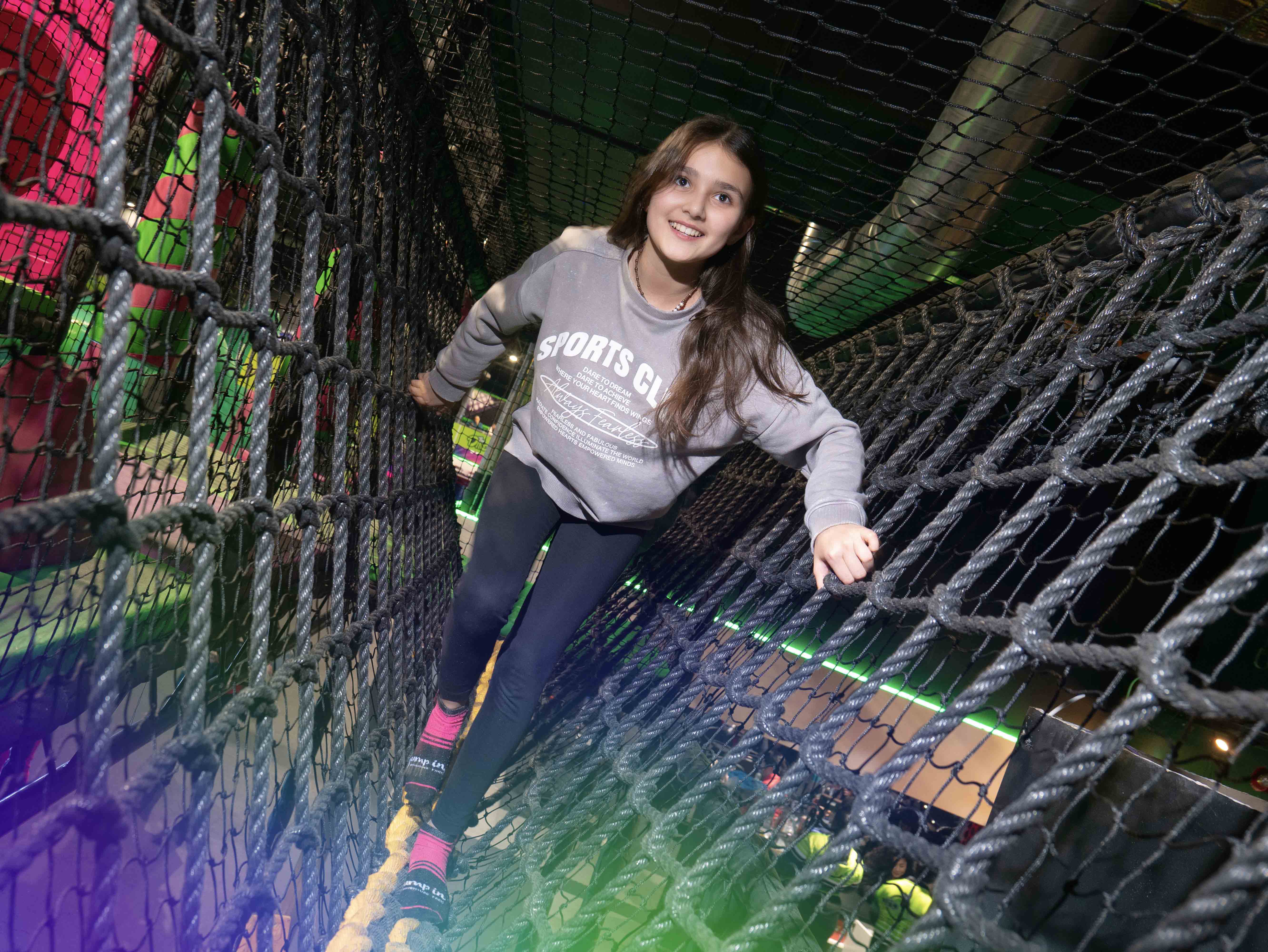 young girl climbing through play area, rope bridge at Flip Out Adventure Park