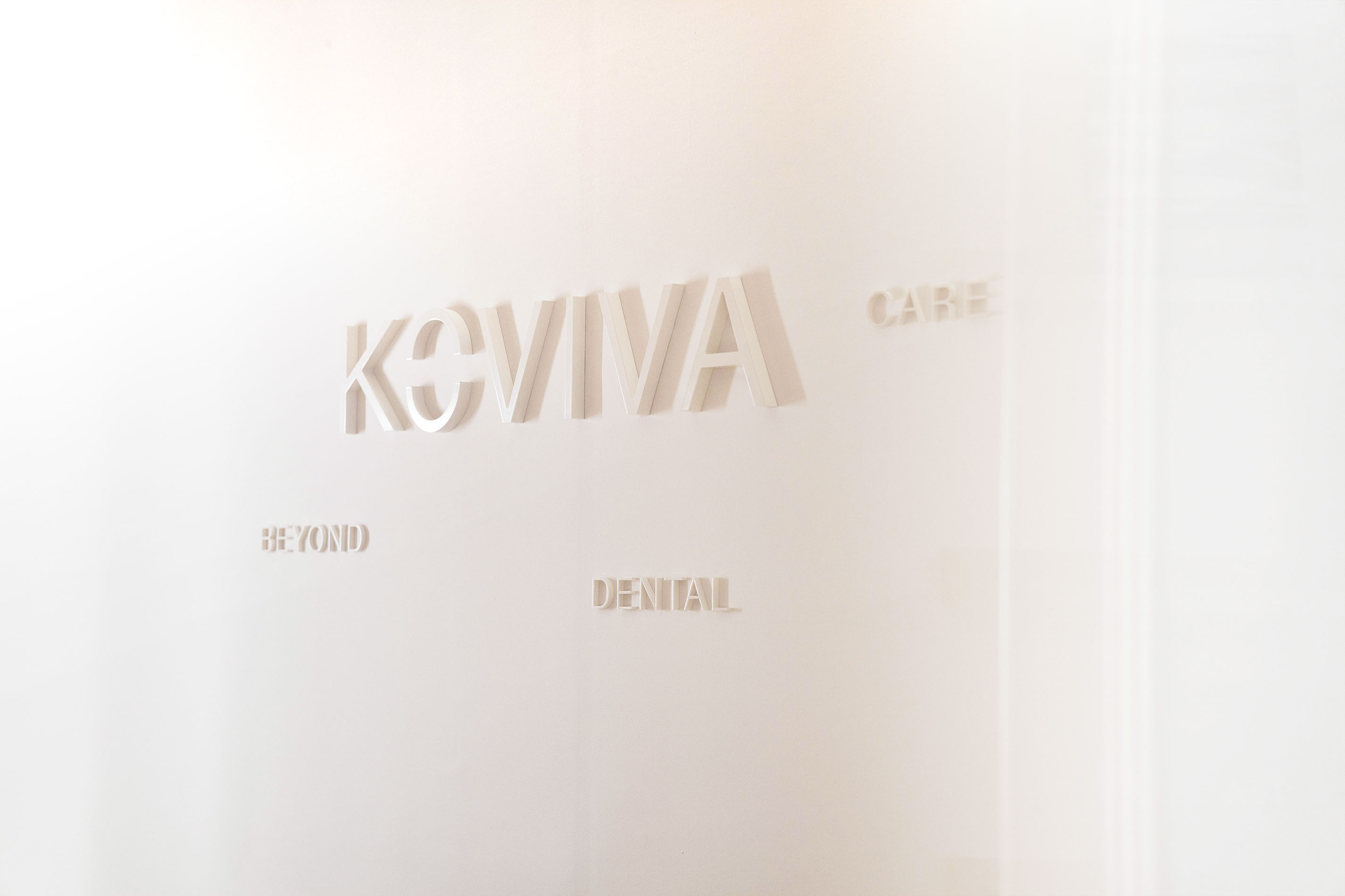 Koviva Dental Logo an weißer Wand. Zahnarztpraxis.