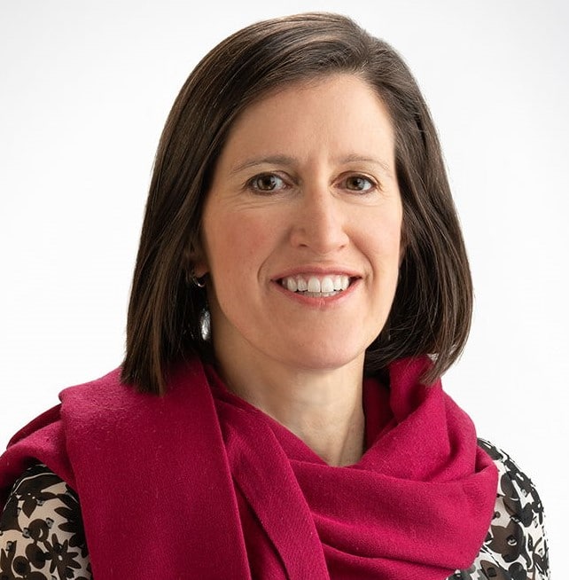 A white woman with a red scarf smiling into the camera