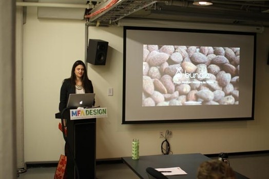A photo of a woman giving a lecture from a laptop while on the screen projector there is a rock texture photo with some text on it.