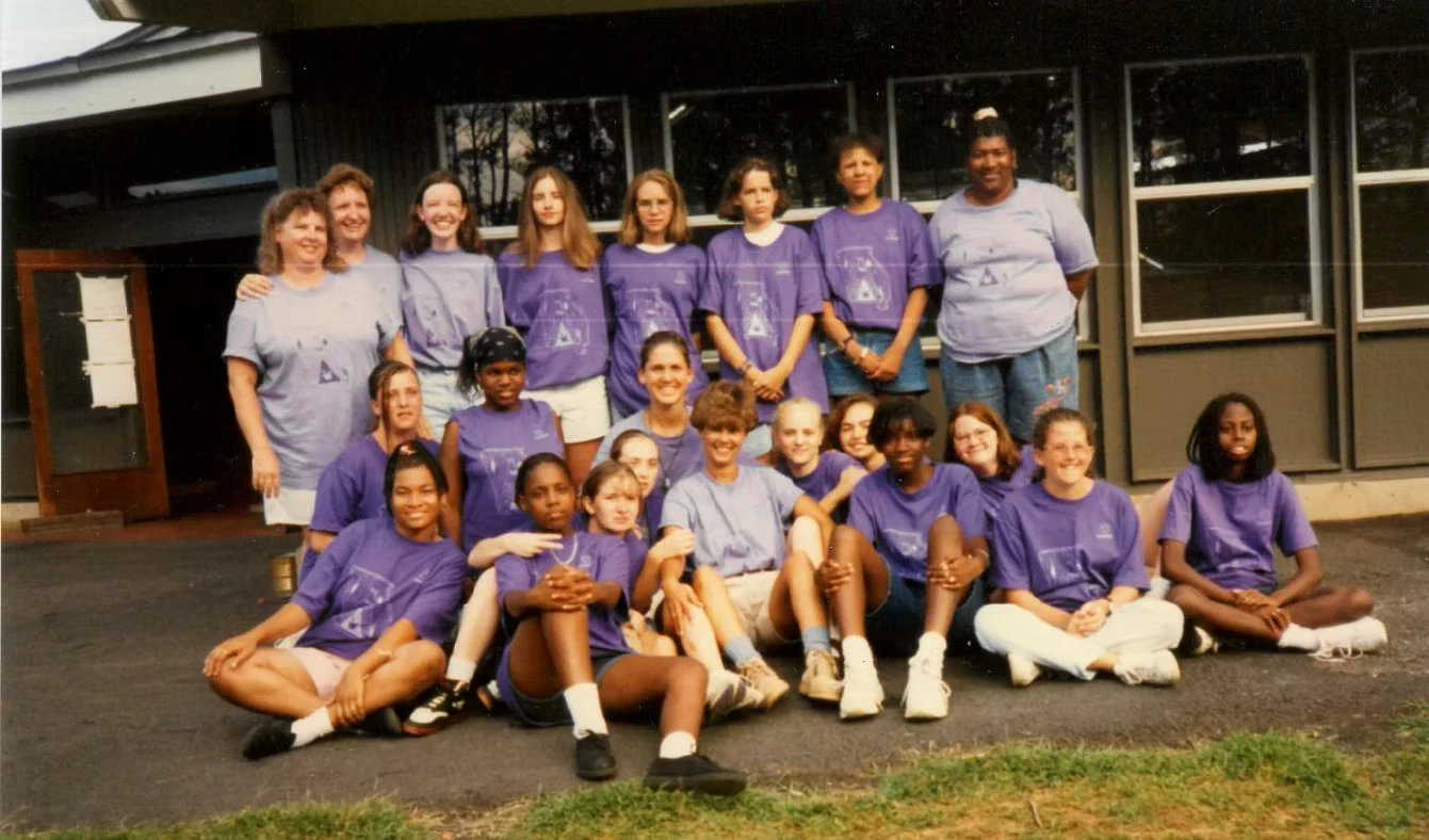 Group photo of campers and staff in purple Camp Juliena t-shirts, posing outdoors in front of a building.