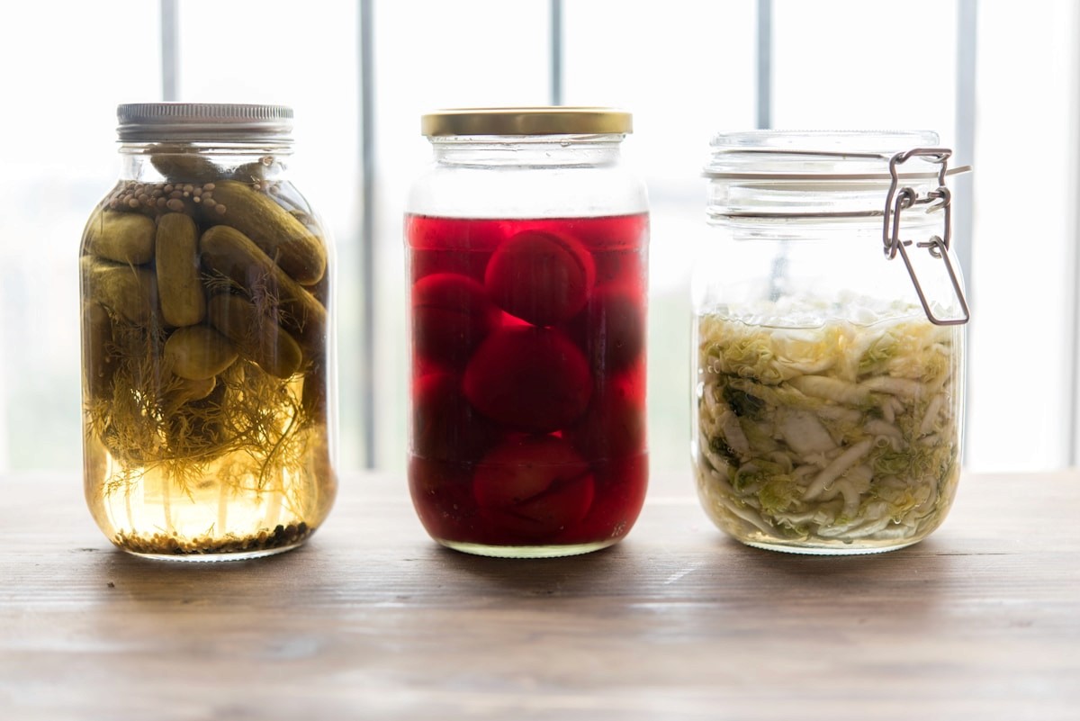 Glass jars of fermented foods including pickles, beets, and sauerkraut, which support gut health and the microbiome