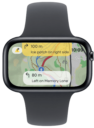 A smartwatch screen displaying a trail map with a yellow warning for ‘100 m — Ice patch on right side’ and a direction reading ‘80 m — Left on Memory Lane.’