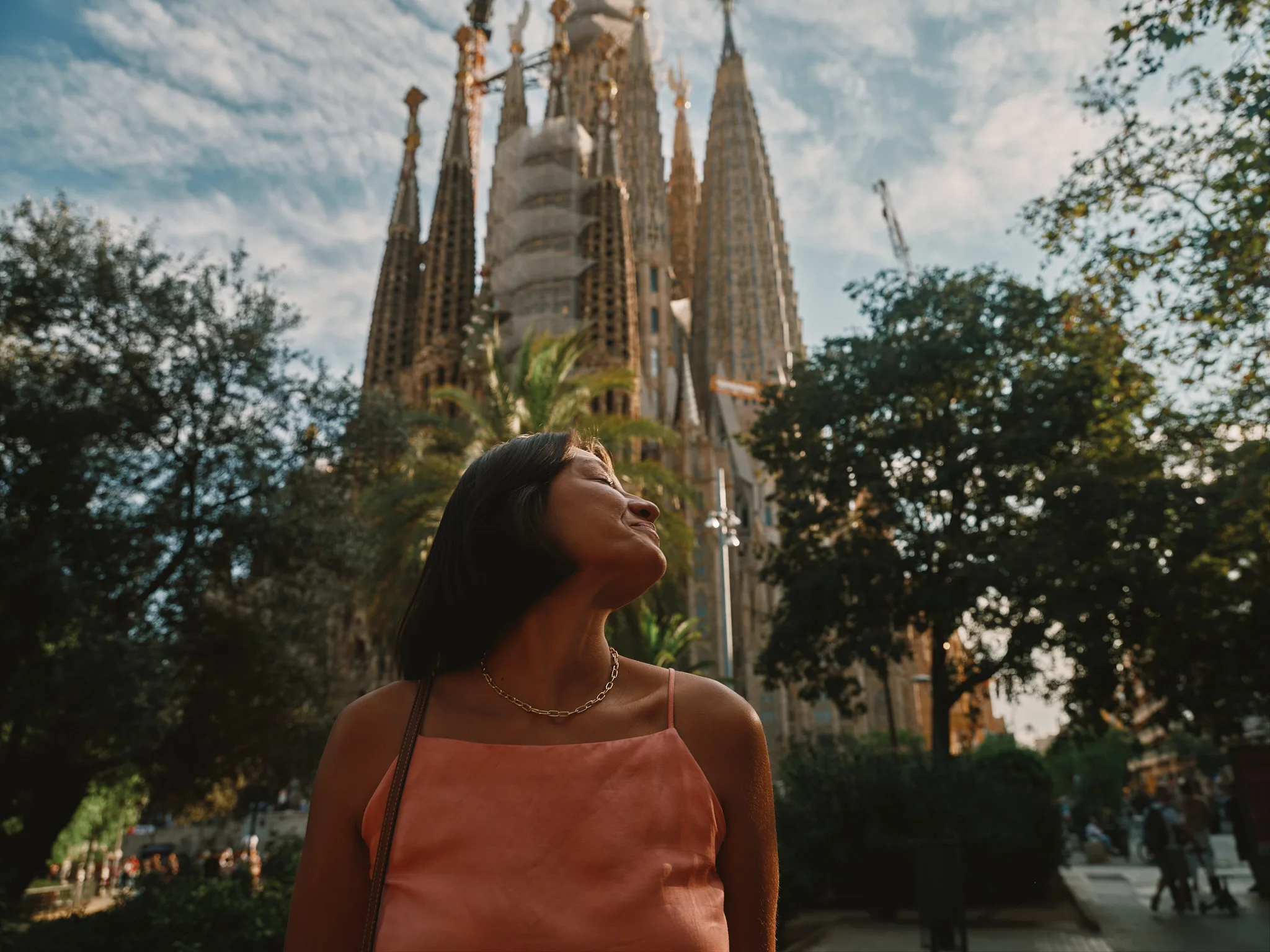 woman tilts face to sun near sagrada familia — lifestyle photography by Tom Kubik