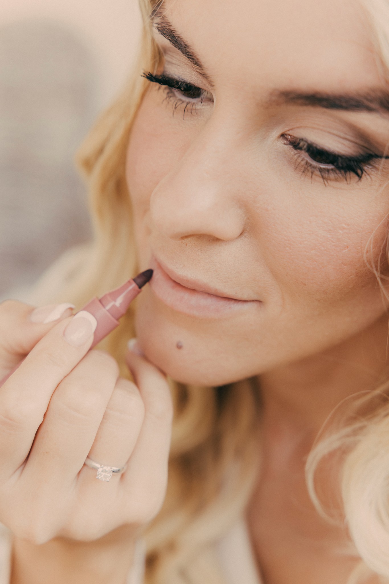 Sposa si ritocca il rossetto, dettaglio dei preparativi matrimoniali a Bolgheri, mano con fede nuziale