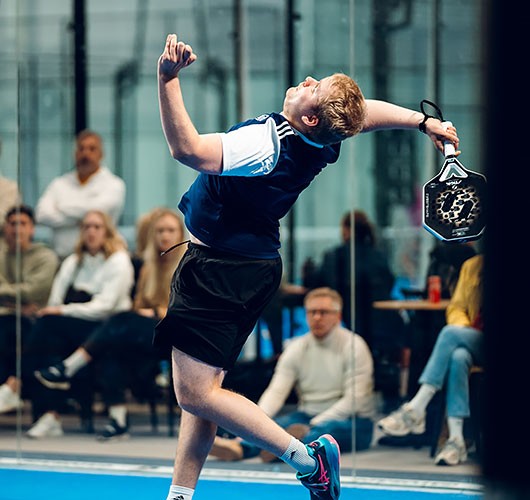 Antti Kampman padel-kentällä lyömässä smashia
