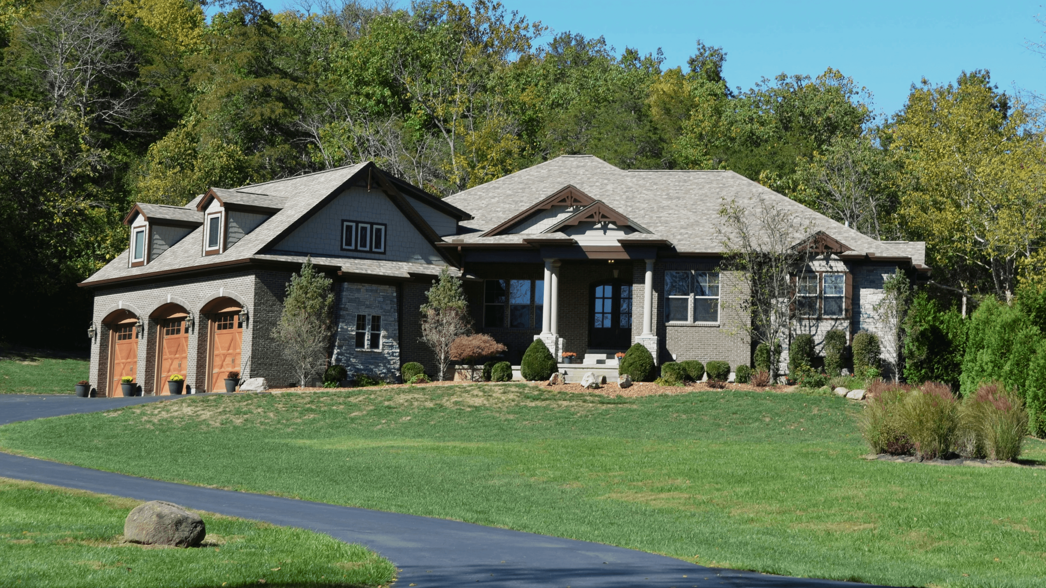 A custom built home on lush green acreage outside of Oklahoma City, the sun is shining and the skies are blue with trees surrounding the well-maintained property.
