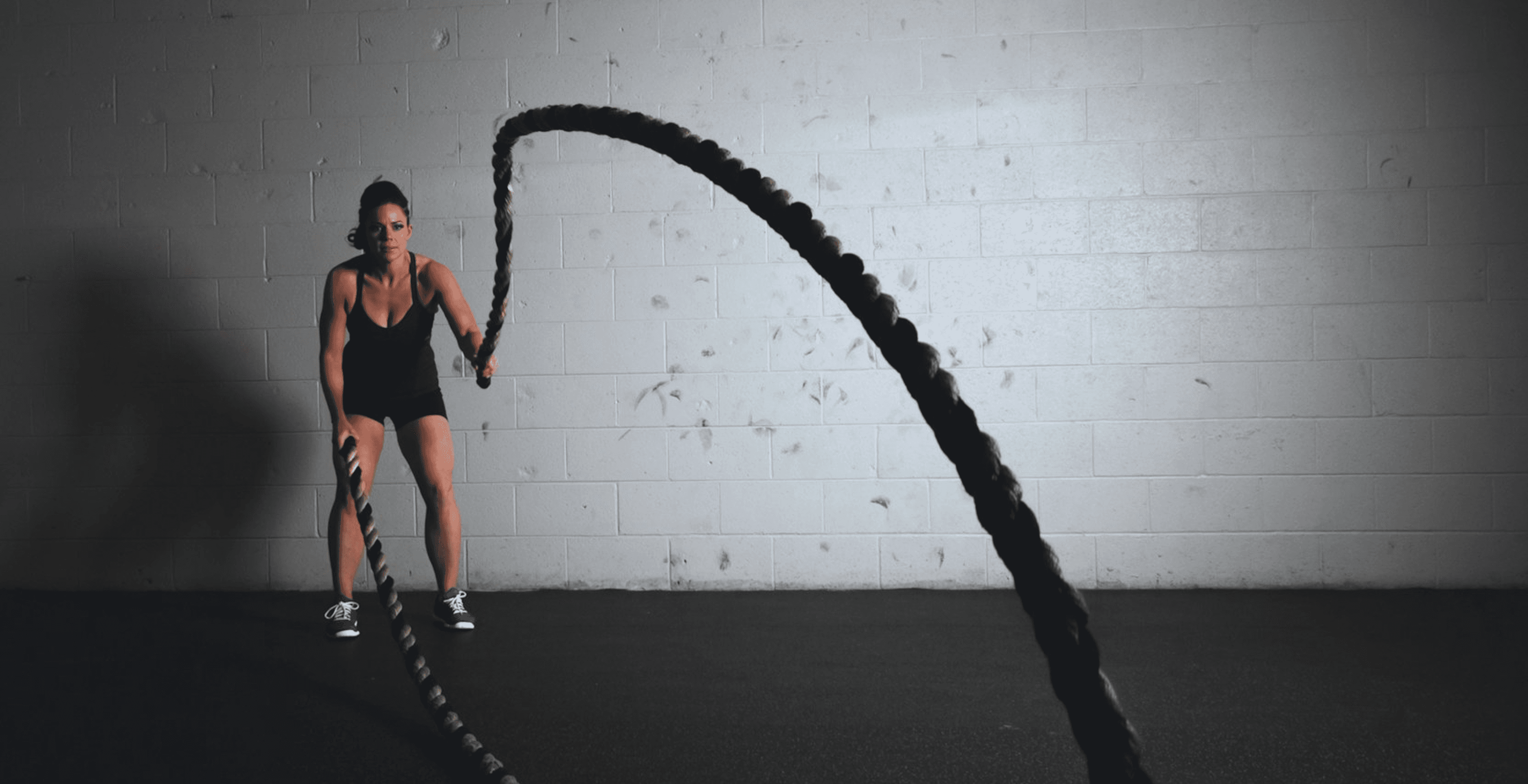 Athlete training with battle ropes in a gym, showcasing strength, movement, and full-body workout.