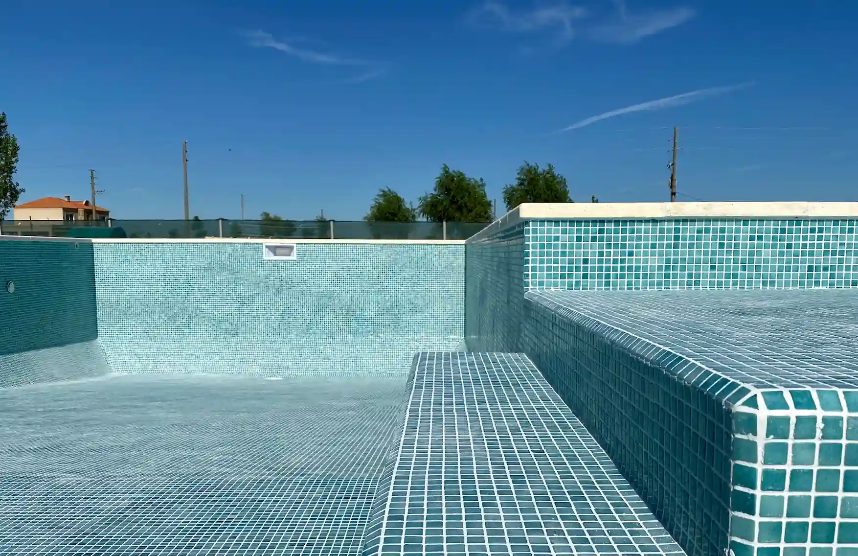 Piscina de hormigón en plena construcción mostrando la terminación impecable de los escalones revestidos con mosaico veneciano color esmeralda.