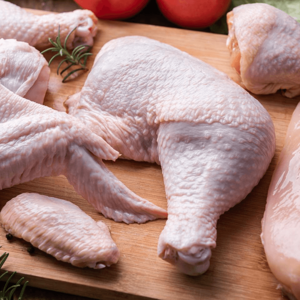 A smiling woman with her arms crossed, standing against a dark green background. She has long, dark hair.