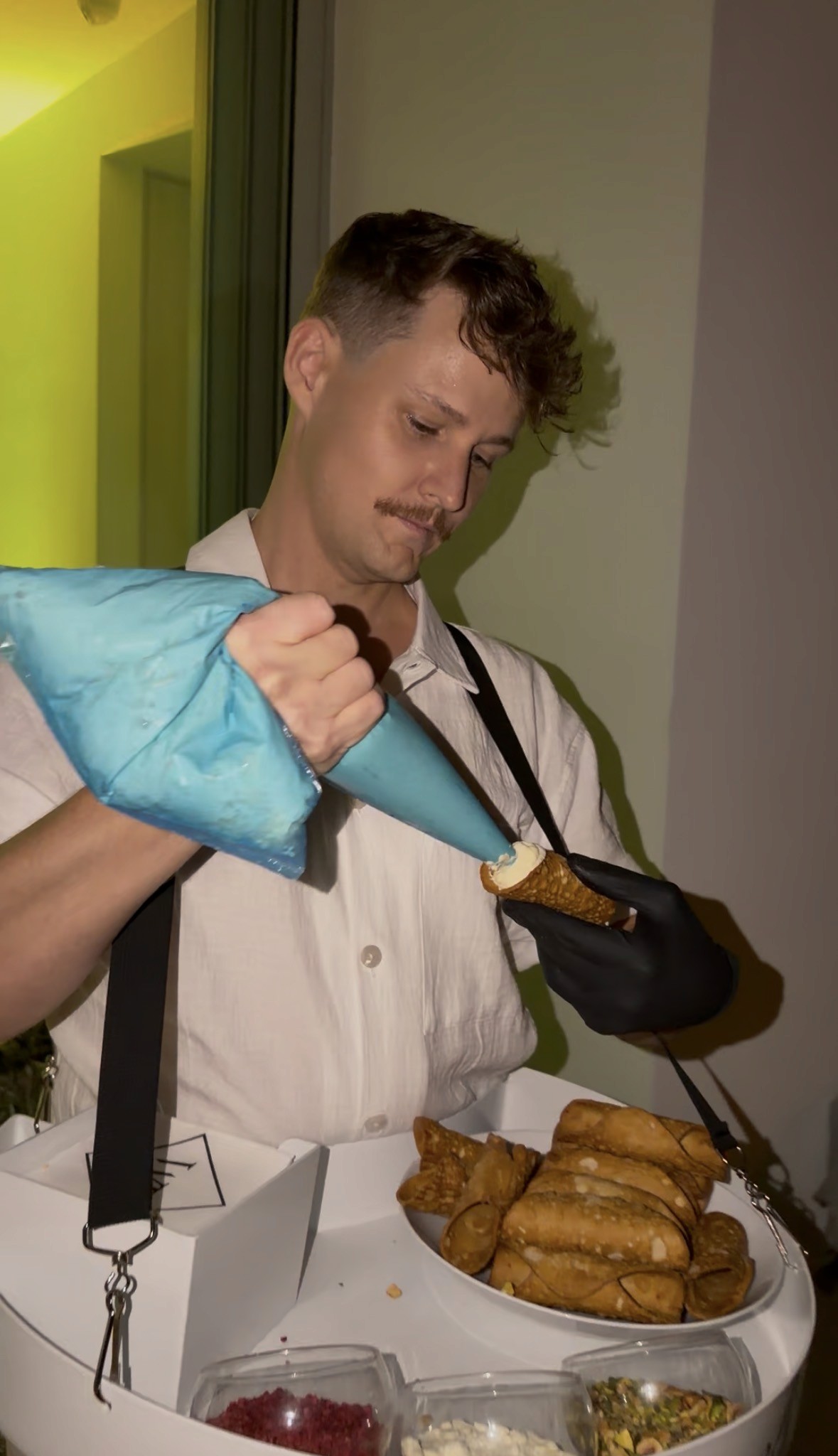 Roaming cannoli waiter filling cannolis live for guests at a canape event