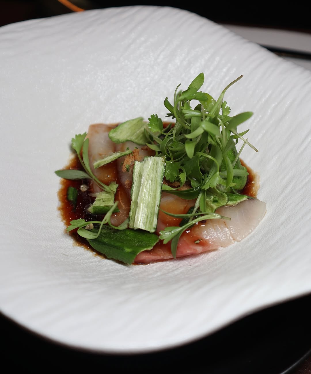 "A refreshing dish featuring fresh greens and thinly sliced fish, drizzled with a light, flavorful dressing. One of the many creative and seasonal offerings at Toka Chef in NYC."