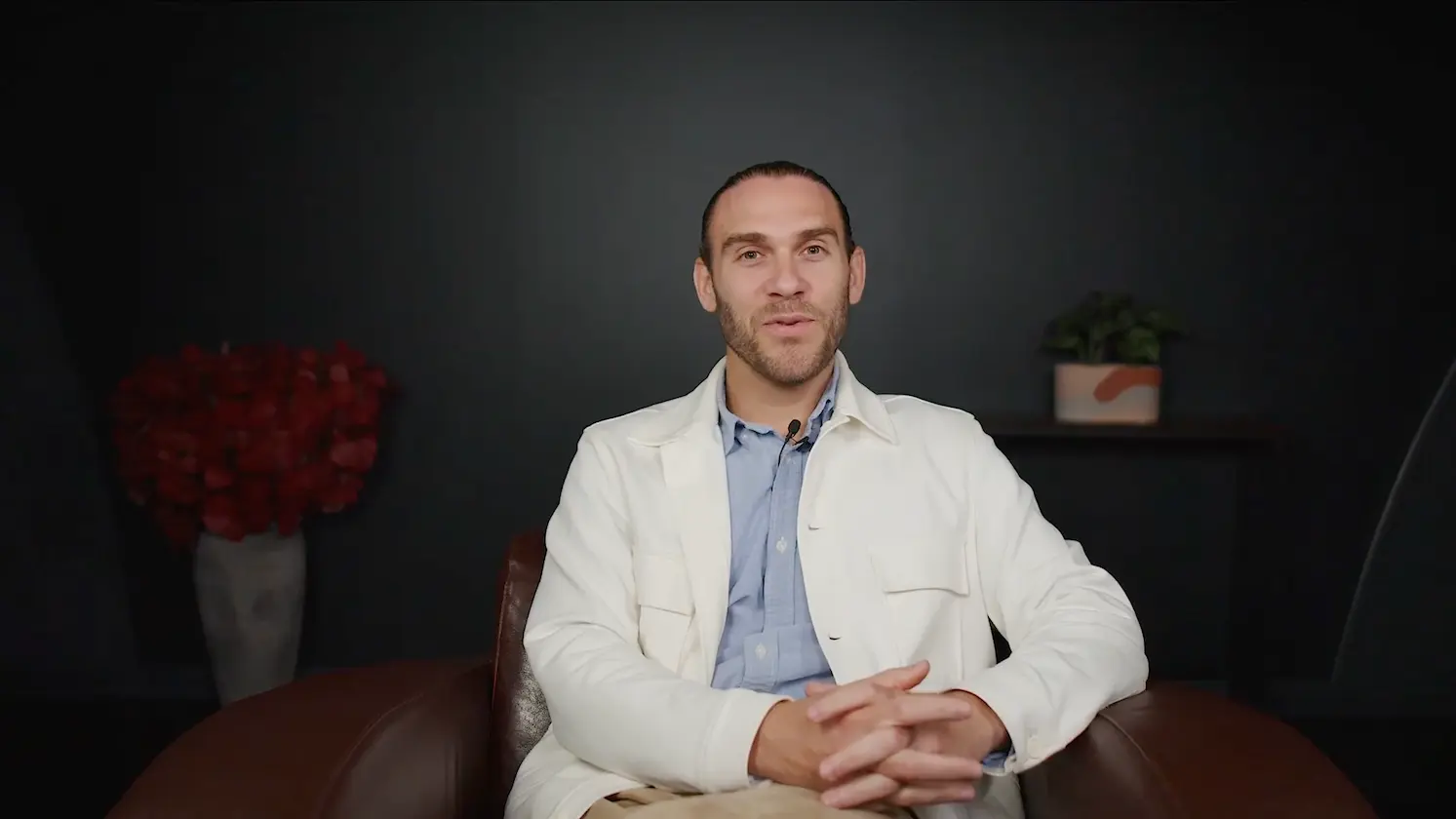 Homme assis dans un fauteuil en studio, face caméra, parlant de développement personnel et de croyances limitantes au travail