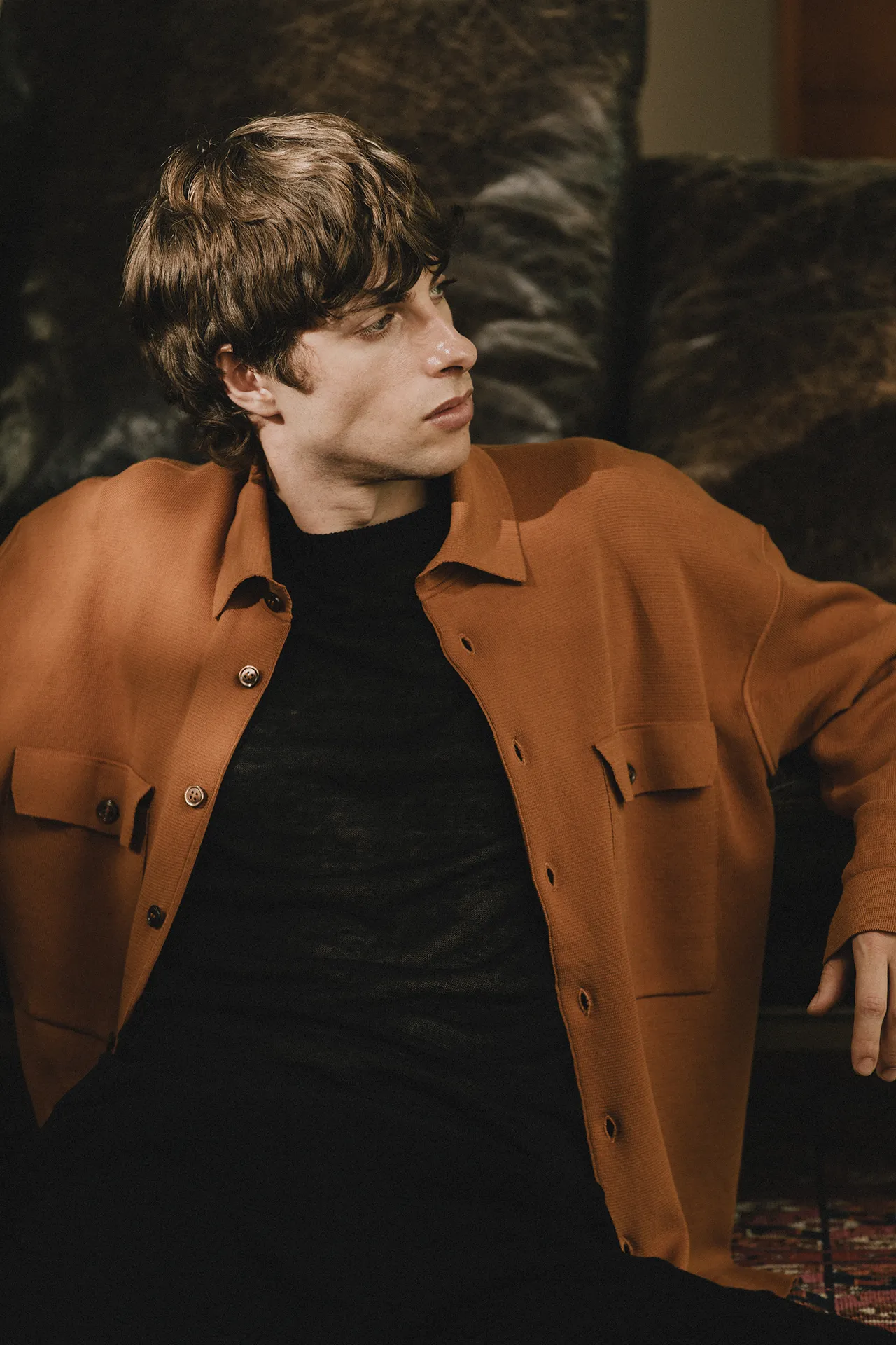 Close-up of Annapurna SS26 collection rust-colored knit jacket with chest pockets and button details.