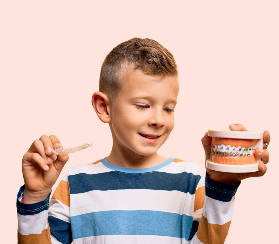 Gutt holder tannmodell med tannregulering og viser hvordan man pusser tennene riktig.