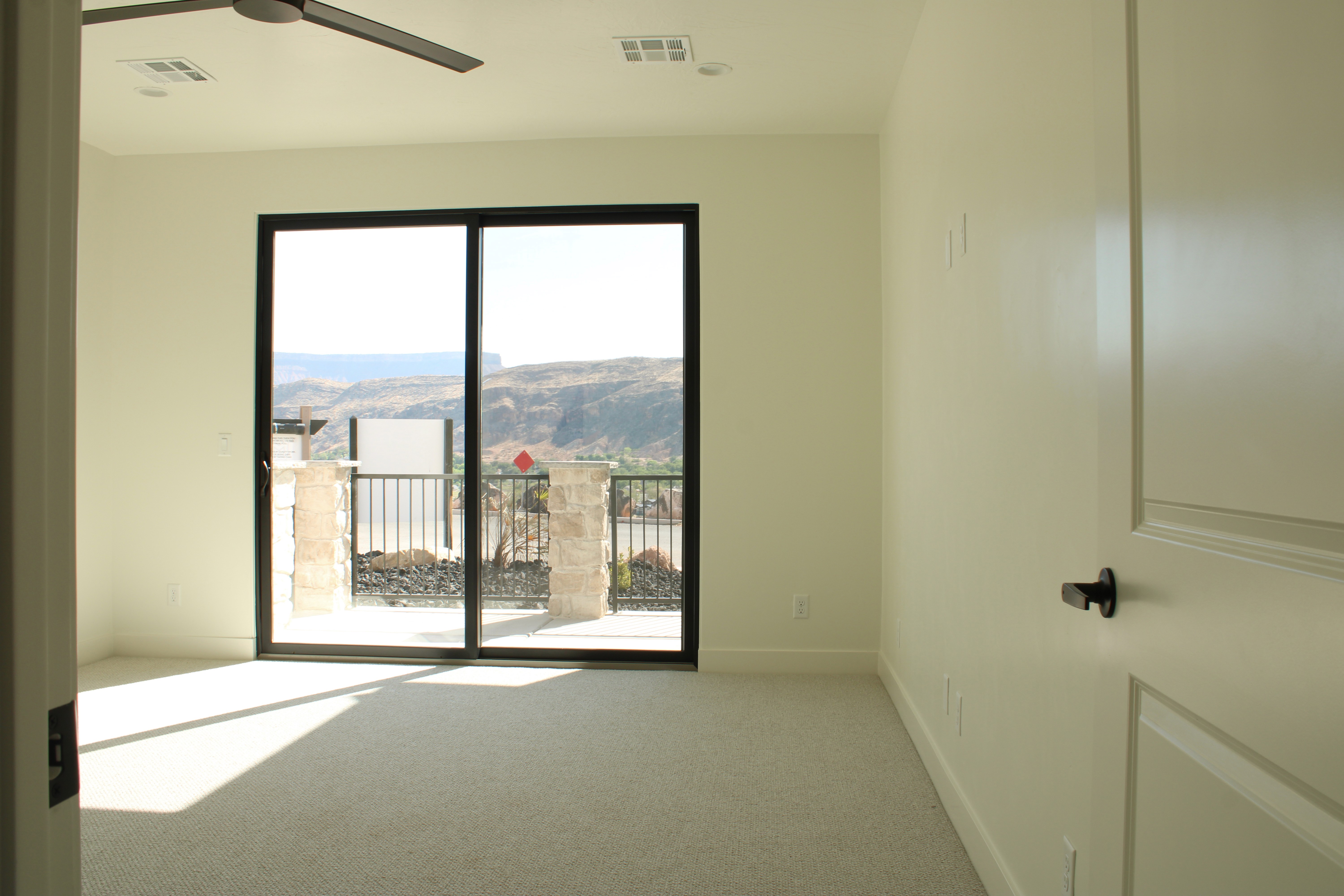 Spacious master bedroom in The Overlook at Falcon Ridge, Hurricane, Utah, showcasing clean lines and a sliding door opening to the patio.