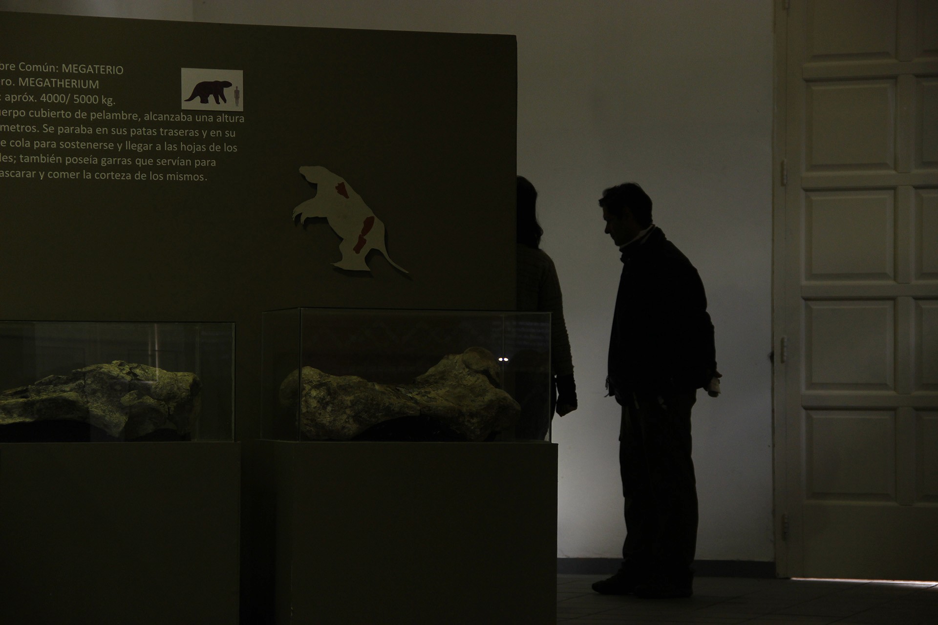Black and white photo of two people looking at a computer screen with papers on wall