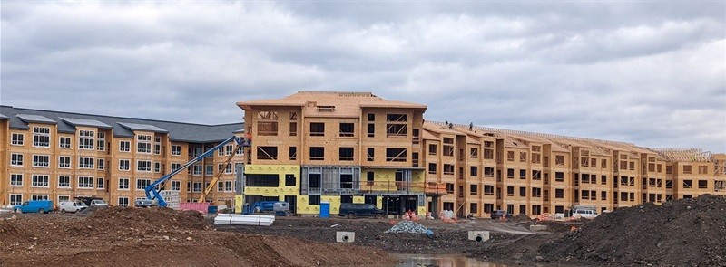 Active construction site of a massive multi-story building showing extensive exposed wood-framing, representing M-Fire's core fire retardant application phase.