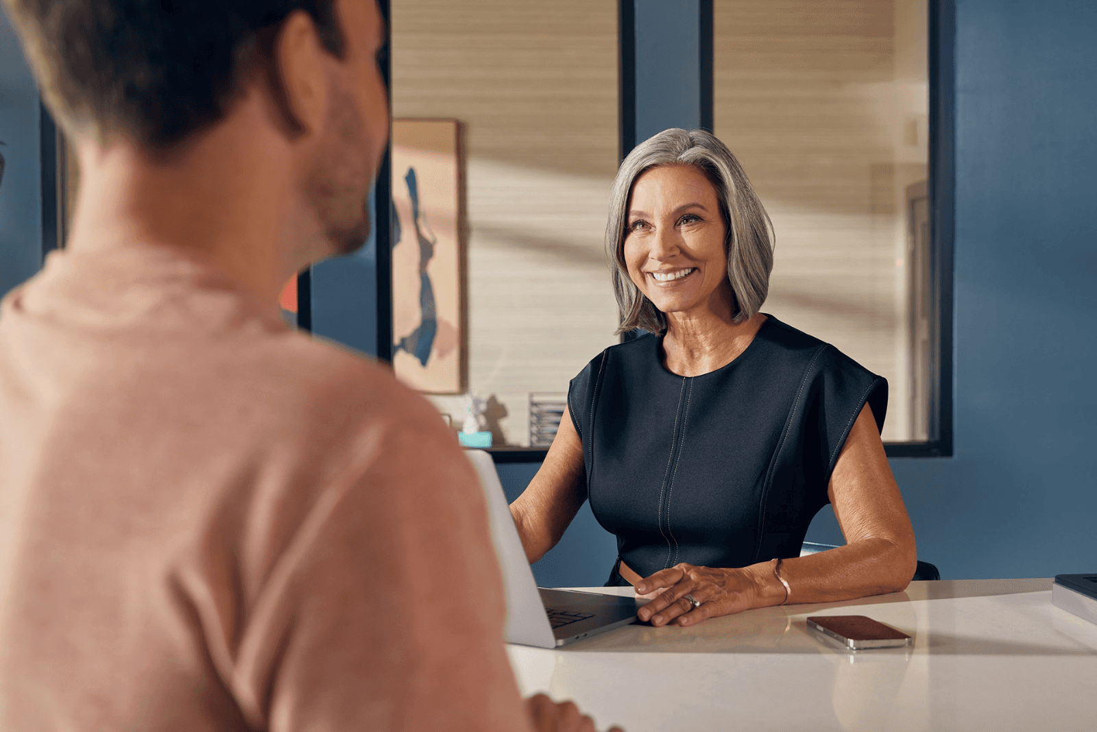 Leasing agent smiling across a desk at a prospective resident, SmartRent marketing still by Inquire