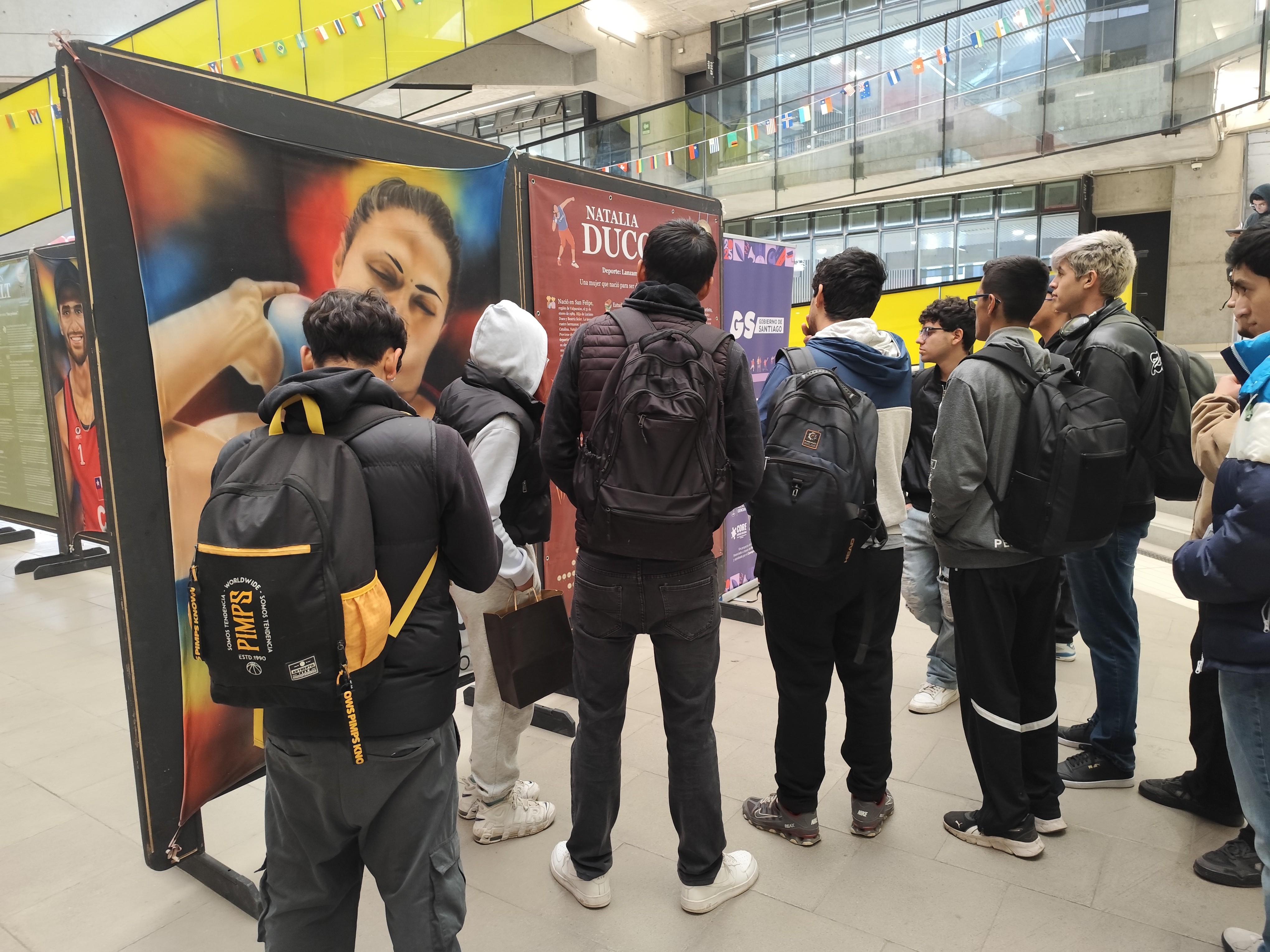 Espectadores contemplando la pintura de Natalia Duco, lanzadora de peso chilena, en la exposición Leyendas del Deporte en USACH.