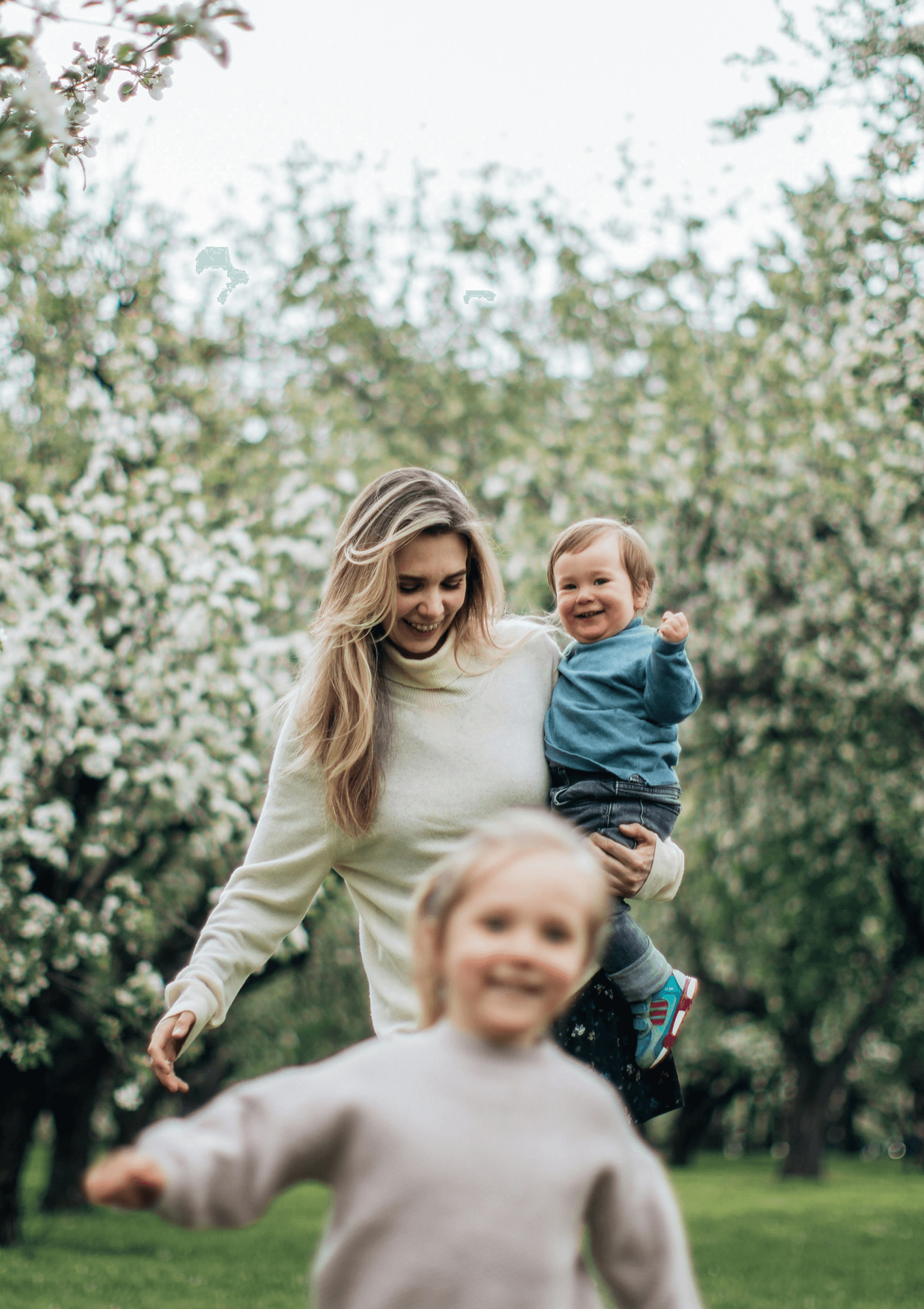 Mom carrying son and walking behind daughter in an orchid