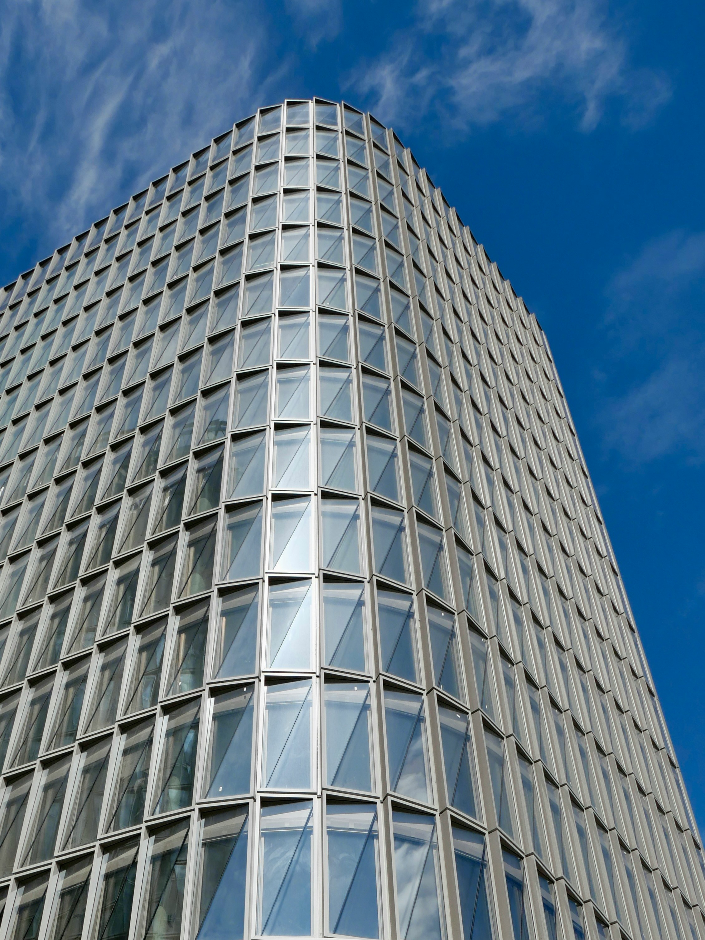 Modern glass building corner against a blue sky