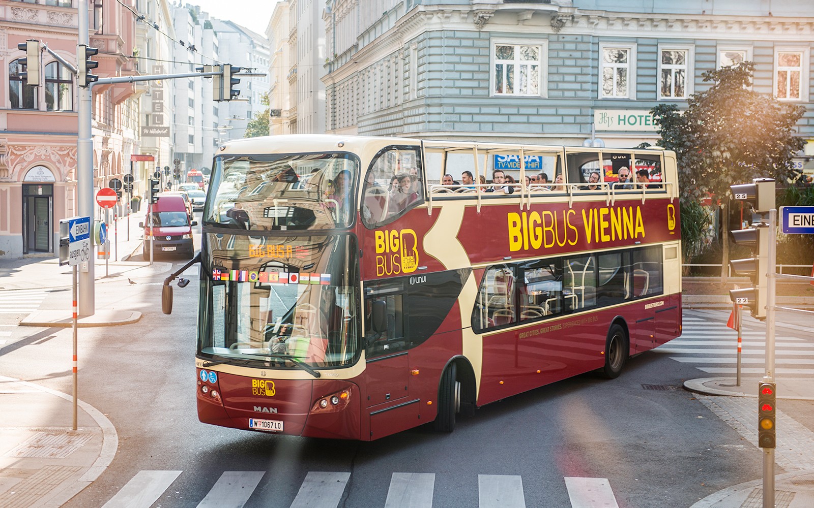 Vienna HopOn HopOff bus on city street with tourists on upper deck.