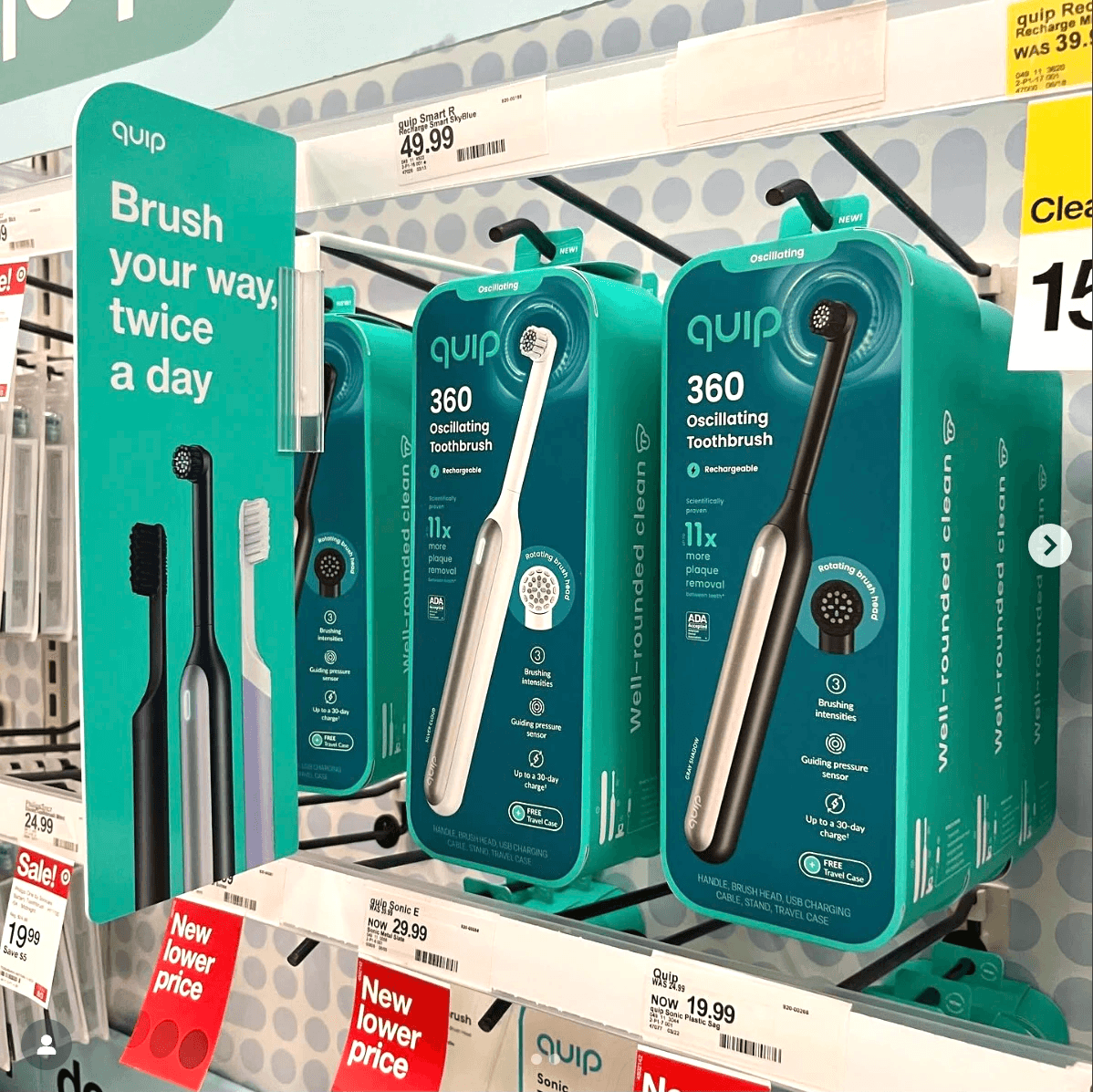 Oscillating toothbrush packages hanging on pegs in a store aisle beside a teal shelf sign