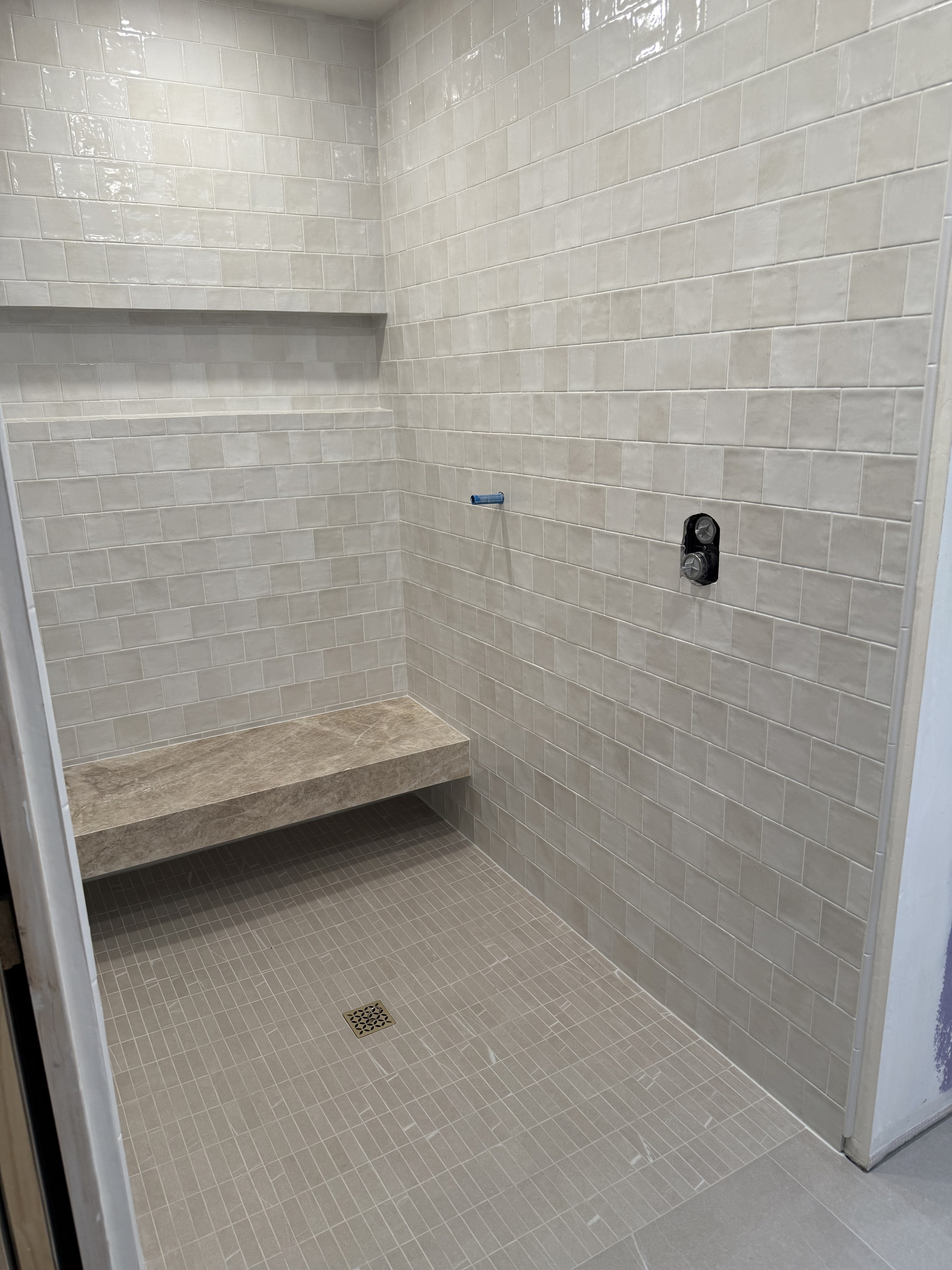 Luxurious bathroom vanity area with a dramatic wall featuring large format natural stone tiles in varying earthy tones and complex veining, serving as a striking backsplash above a double sink vanity.