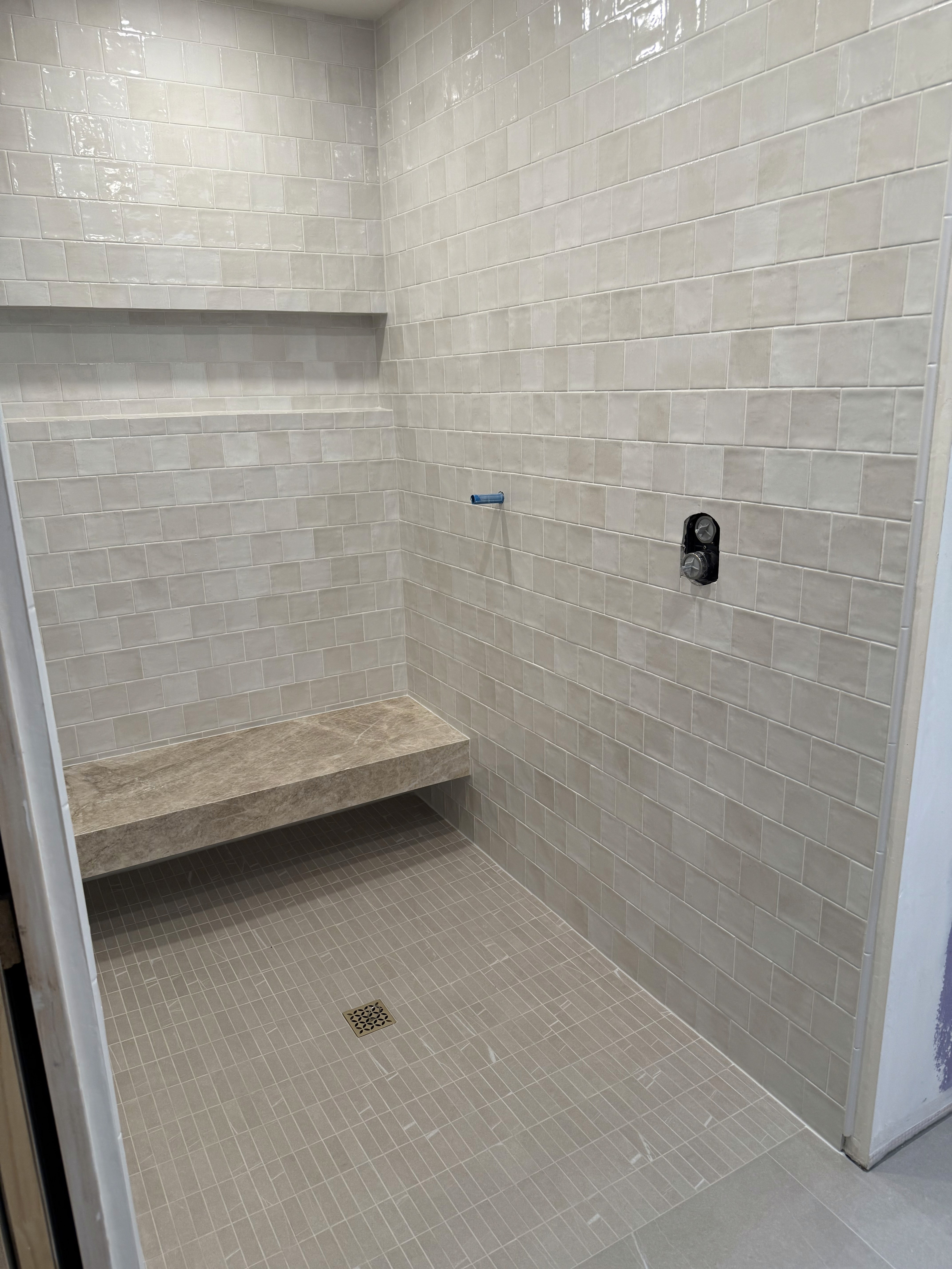 Luxurious bathroom vanity area with a dramatic wall featuring large format natural stone tiles in varying earthy tones and complex veining, serving as a striking backsplash above a double sink vanity.