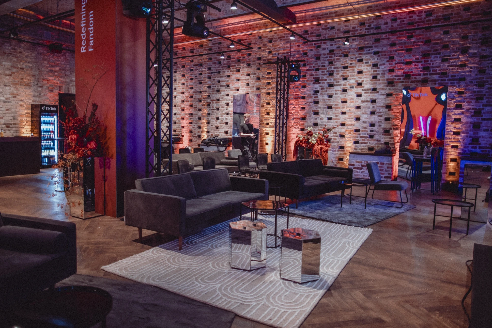 Lounge with velvet sofas, mirrored cube tables and patterned rug in front of brick walls.