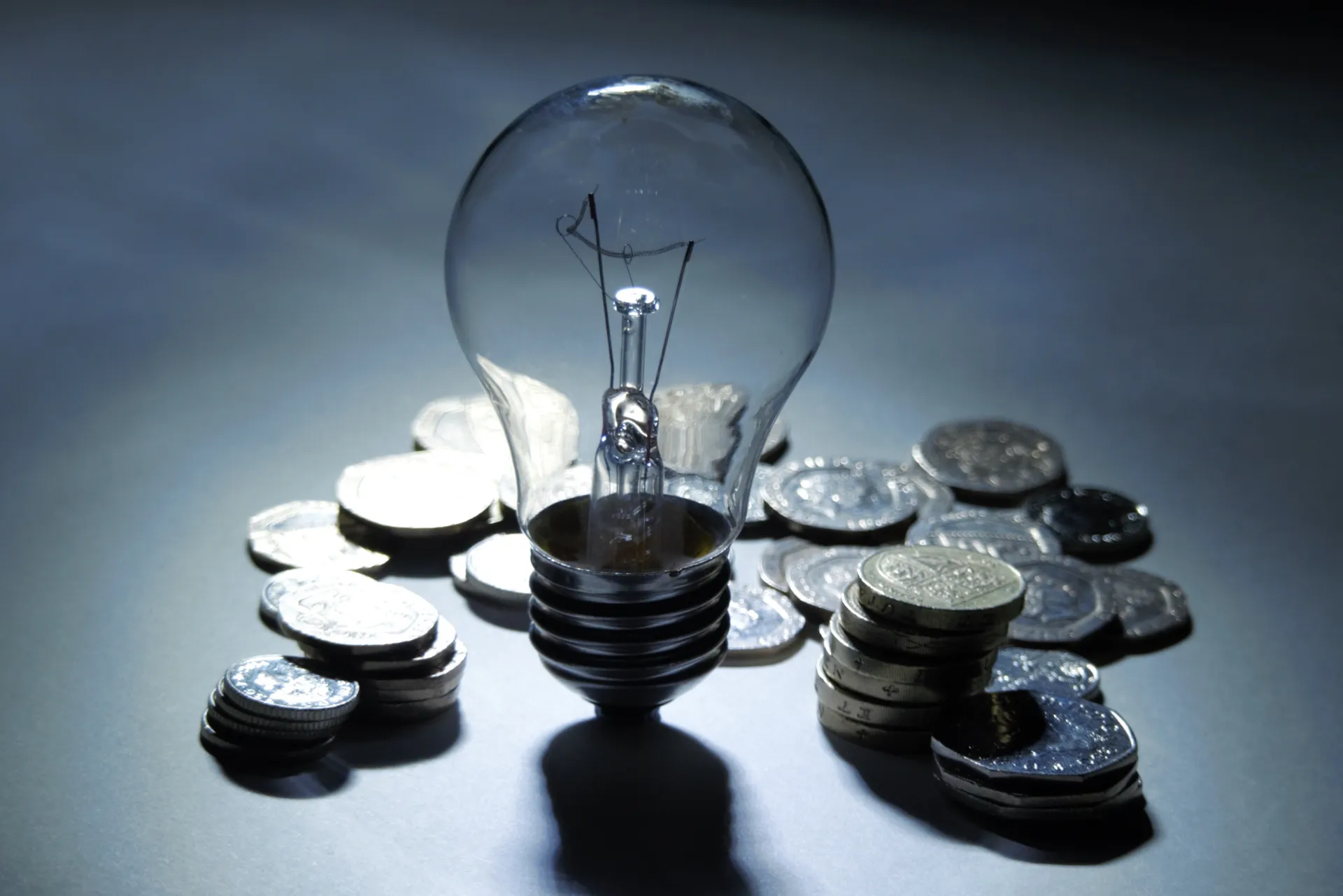 Eine Glühbirne, die auf einem Stapel Münzen platziert ist und Ideen sowie finanzielle Konzepte symbolisiert.