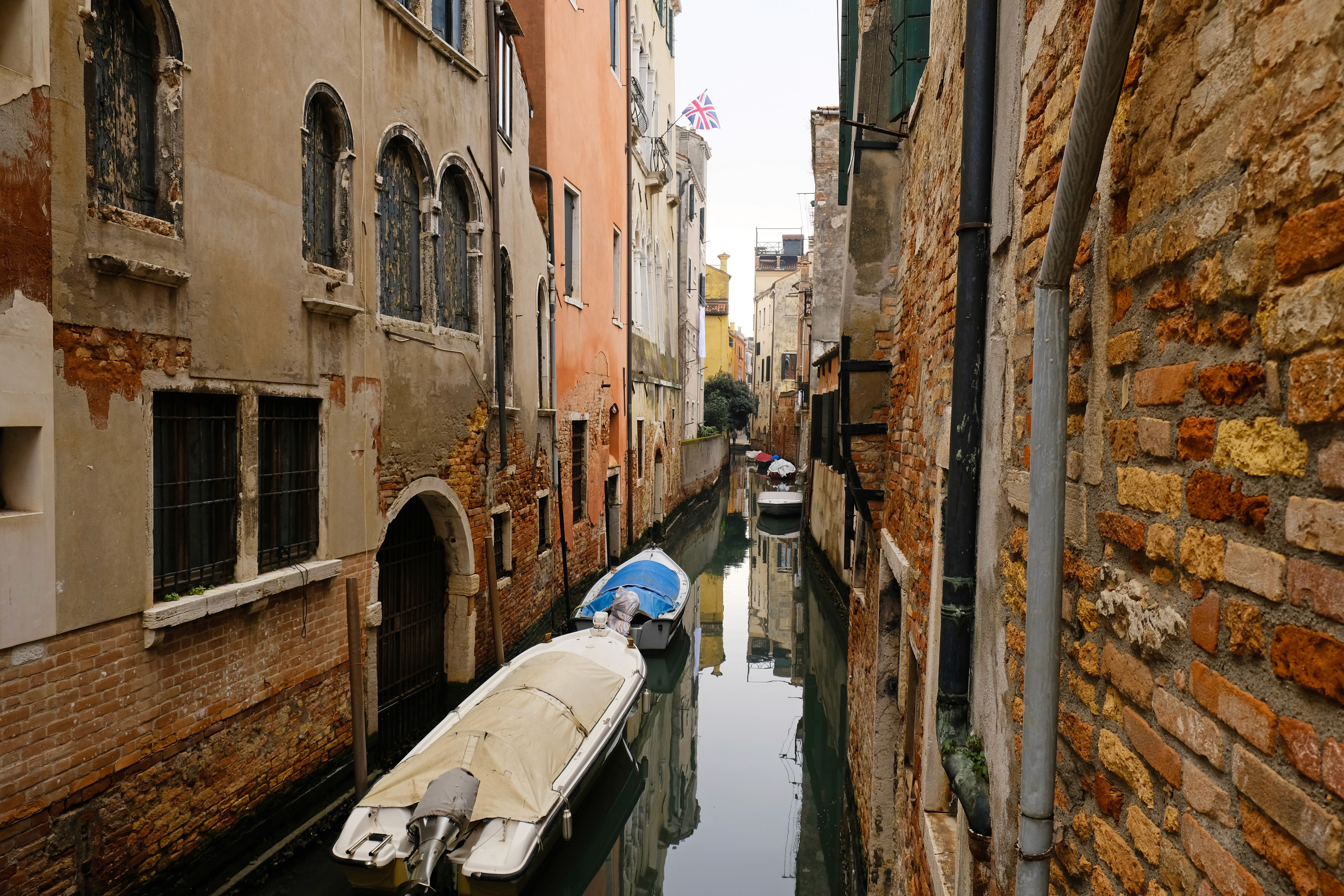 Man wearing glasses writing notes in an open notebook on a speckled tabletop with a cup of coffee nearby.
