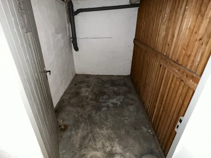 Leeres Kellerabteil mit Holzlattenwand nach der Entrümpelung