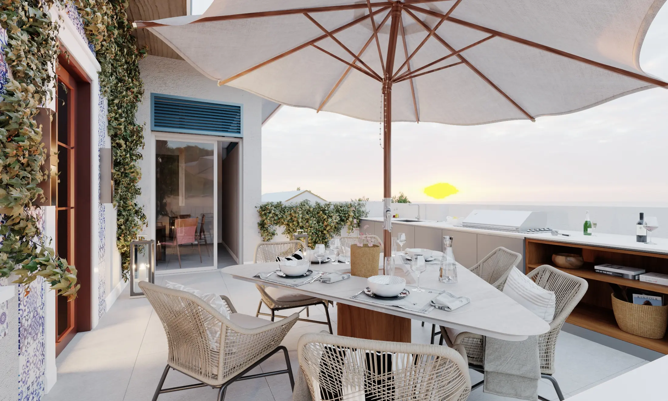 Sunset rooftop patio with a white umbrella over a set dining table, woven chairs, potted plants, and an outdoor kitchen facing the ocean.