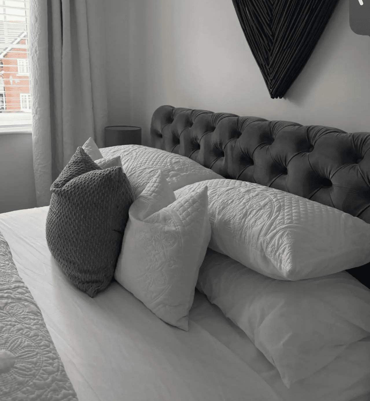 A professionally made bed with crisp white linens and perfectly arranged pillows, showcasing the fresh bed sheet and linen refresh add-on service.