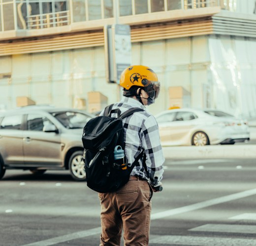 Joven con casco de moto y mochila en la ciudad: seguro de moto o ciclomotor para conductores noveles