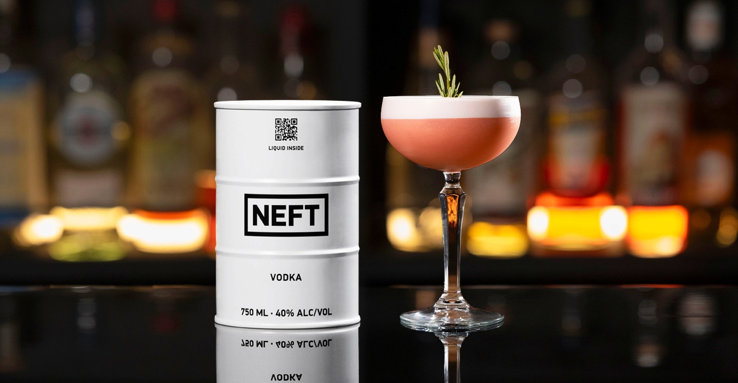 A NEFT Barrel and a glass of Pomegranate Whip on a bar counter.