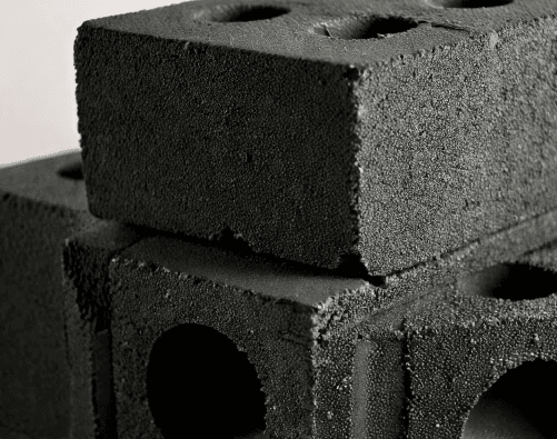 Un gros plan sur des blocs de béton texturés, représentant la solidité et la structure, tout en rappelant l'aspect minimaliste et industriel du festival. Cela fait écho à l’idée de fondations solides et d’un impact durable, un élément clé du festival Solidays.