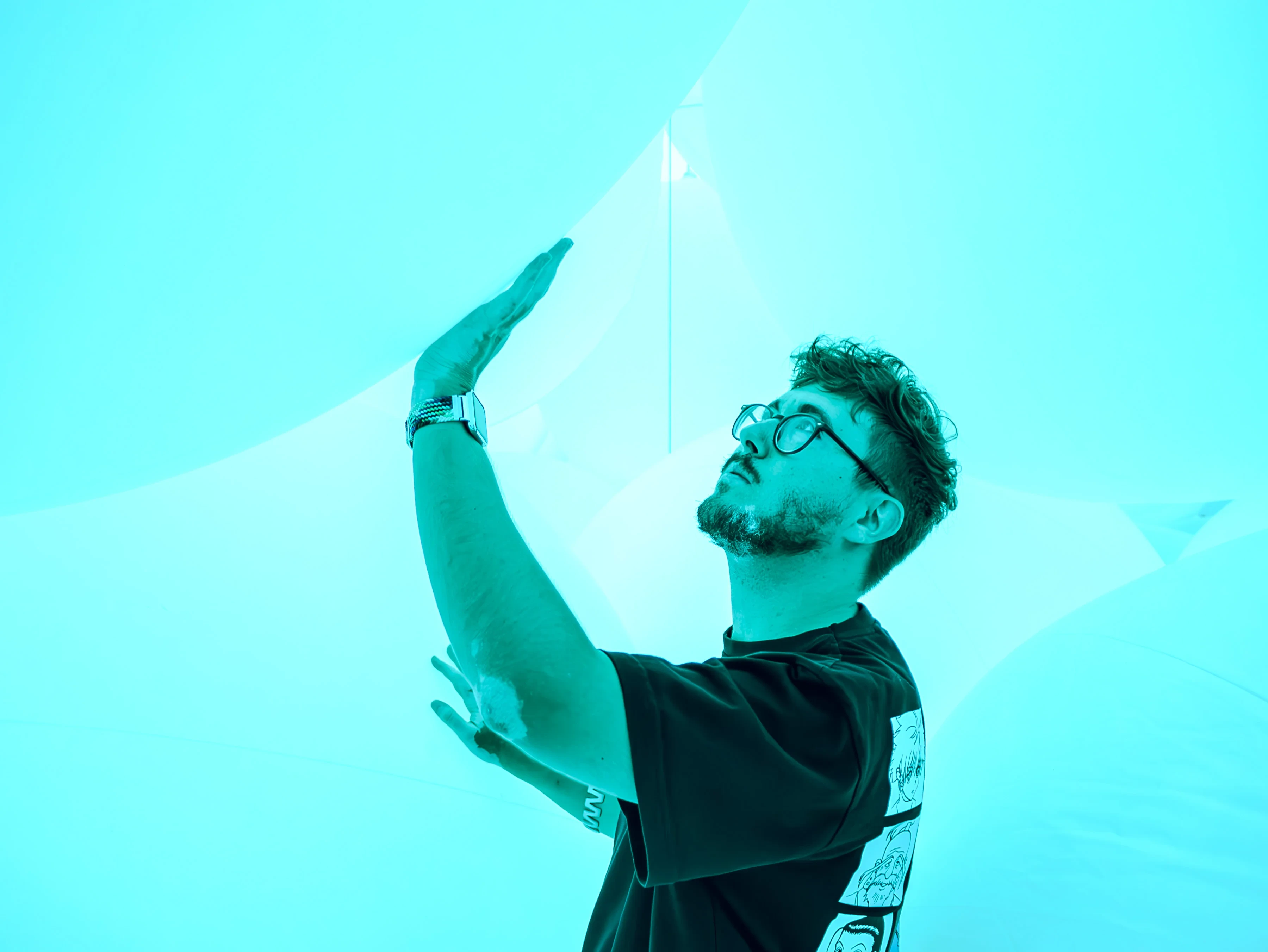 A bespectacled Ismael Casado reaching towards a vibrant blue ball structure.