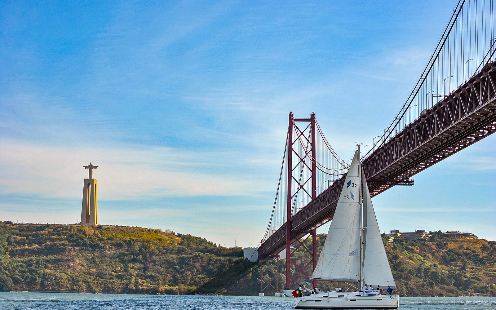 在里斯本的25 de Abril大橋和Cristo Rei雕像附近的塔古斯河上的帆船。